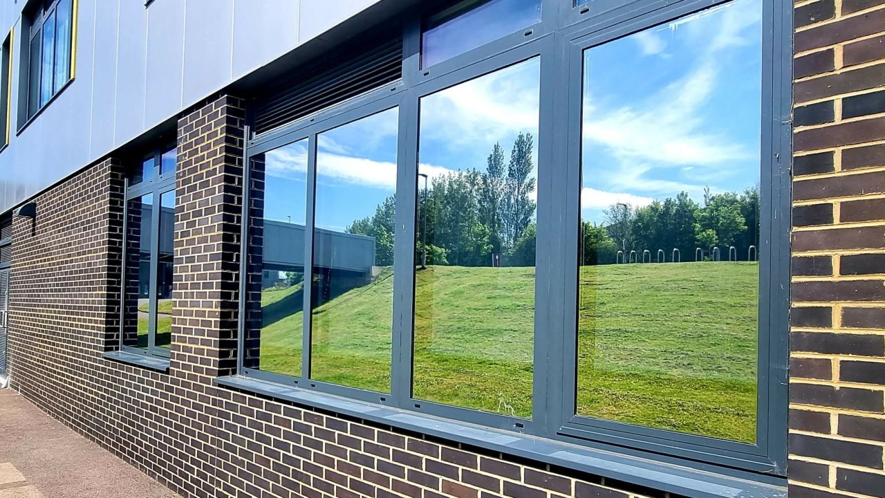 Silver reflective window film on the glazed front of an office building at Kents Hill